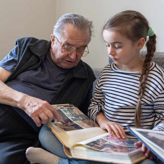 grandad and grandaughter enjoying looking at a photo album of memories