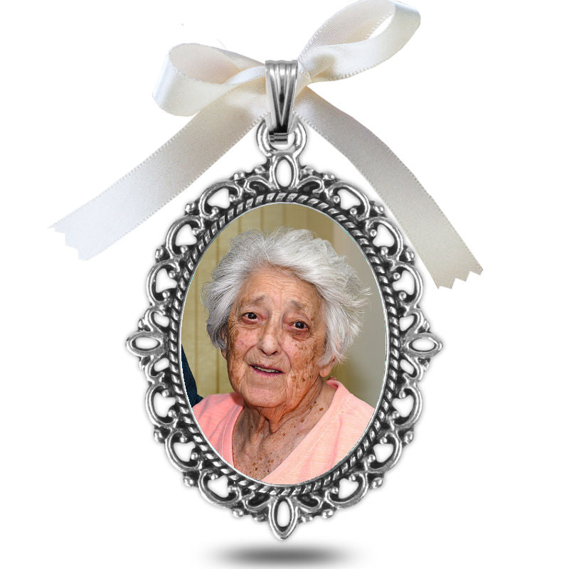 Silver pendant with a photo of an elderly woman and a white ribbon on a white background